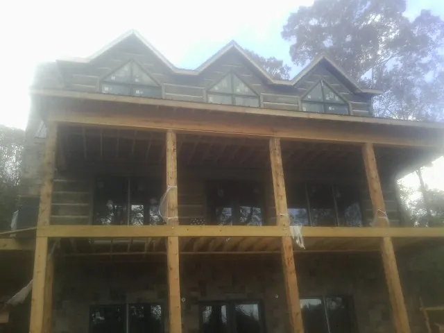 Dormers and porch framing on a large log home under construction — Roof Coating work by our crew in Rockport